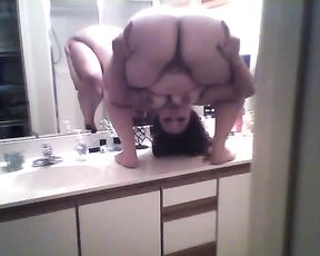 Nude yoga girl doing standing pretzel in the bathroom